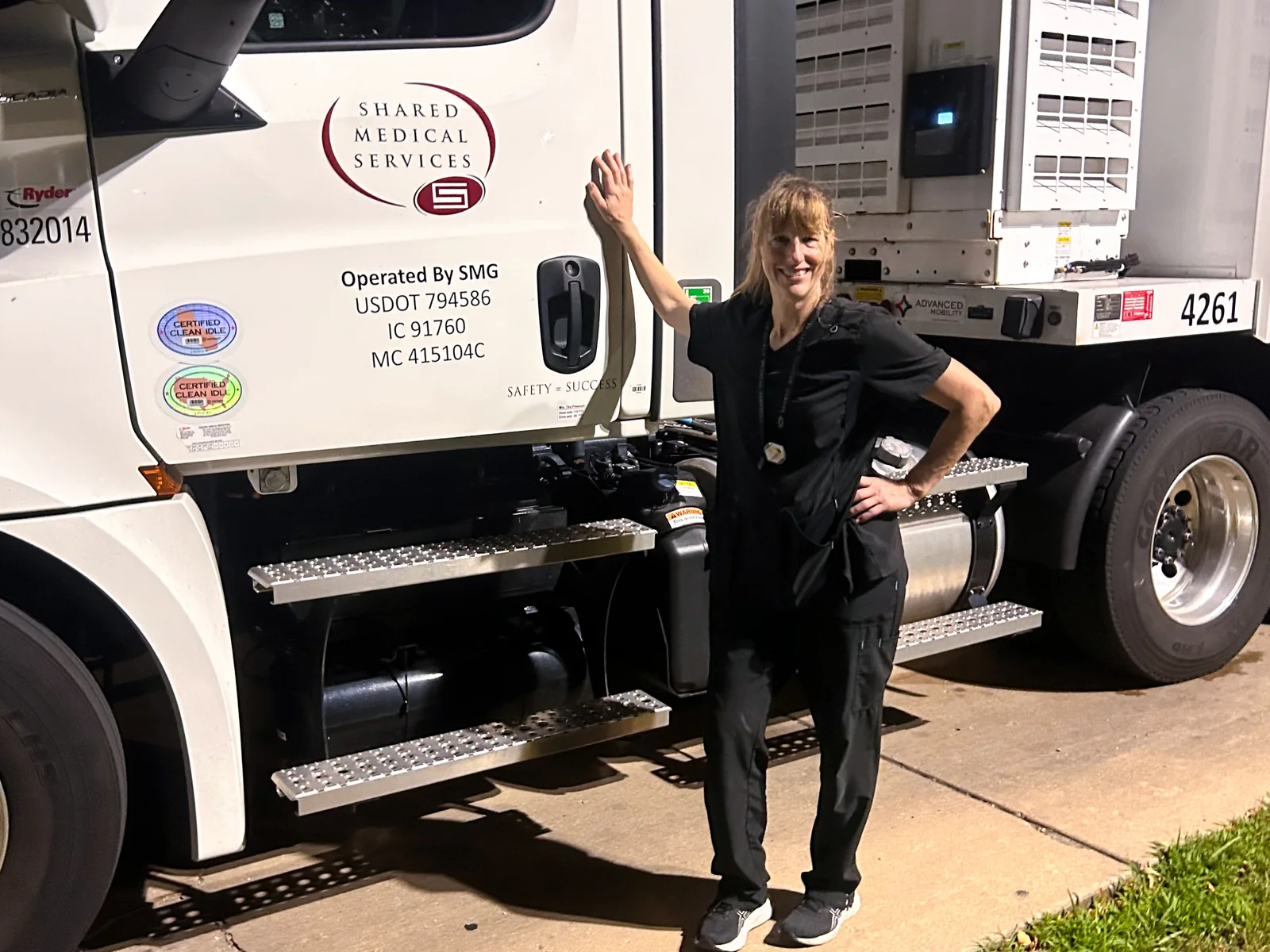An SMS driver standing beside the tractor of a wide bore mobile MRI unit.