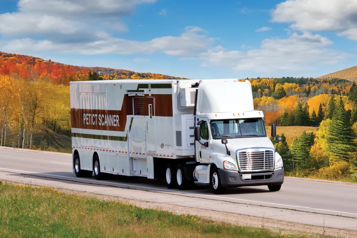 SMS mobile PET scanner truck traveling along a road in autumn.